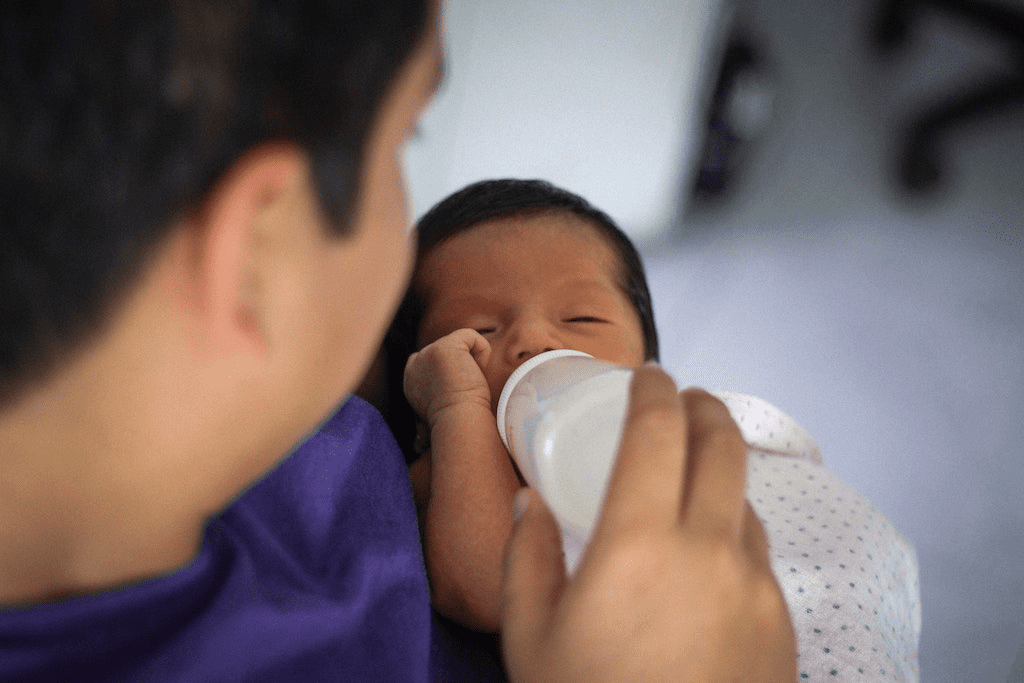 Um bebê tomando leite de mamadeira.