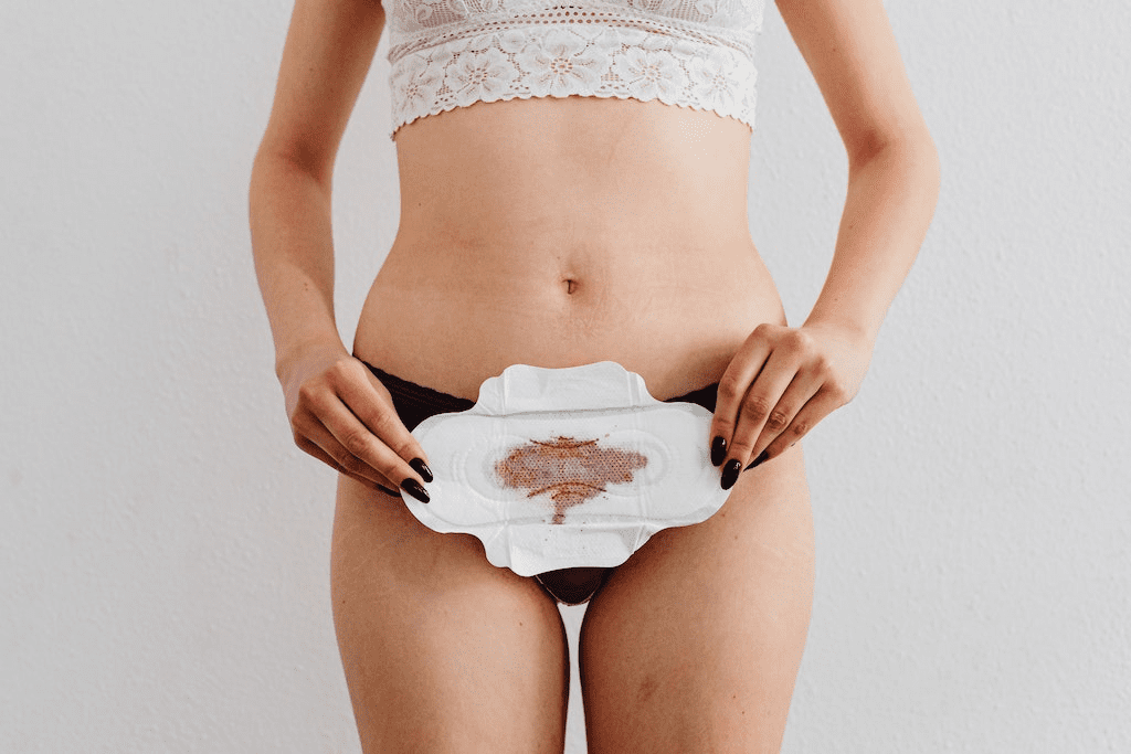 Uma mulher segurando um absorvente menstrual.