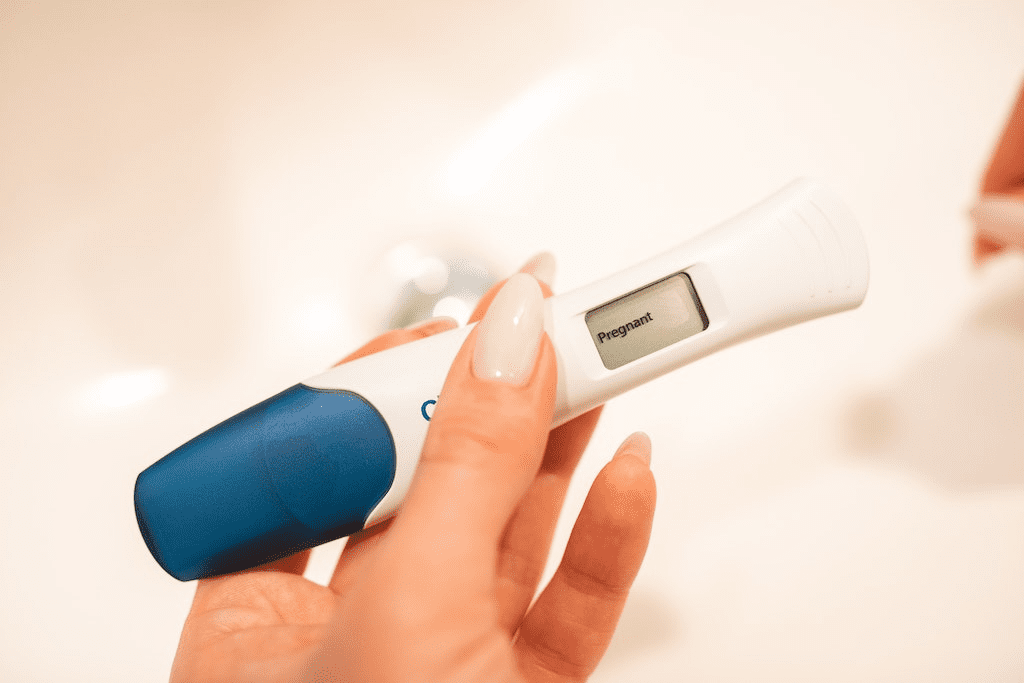 Uma mão de mulher segurando um kit de teste de gravidez digital.