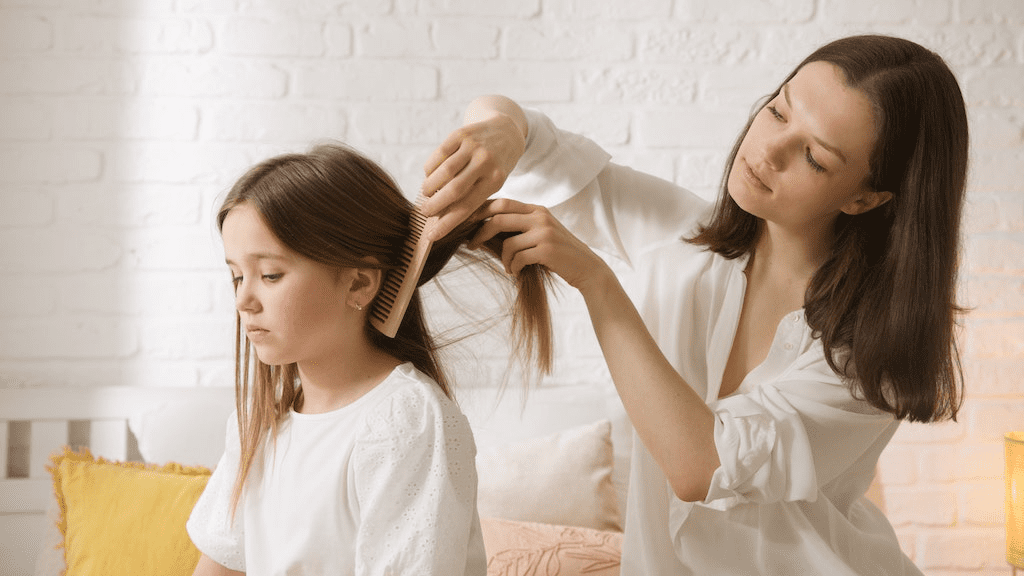Mãe penteando o cabelo da filha.