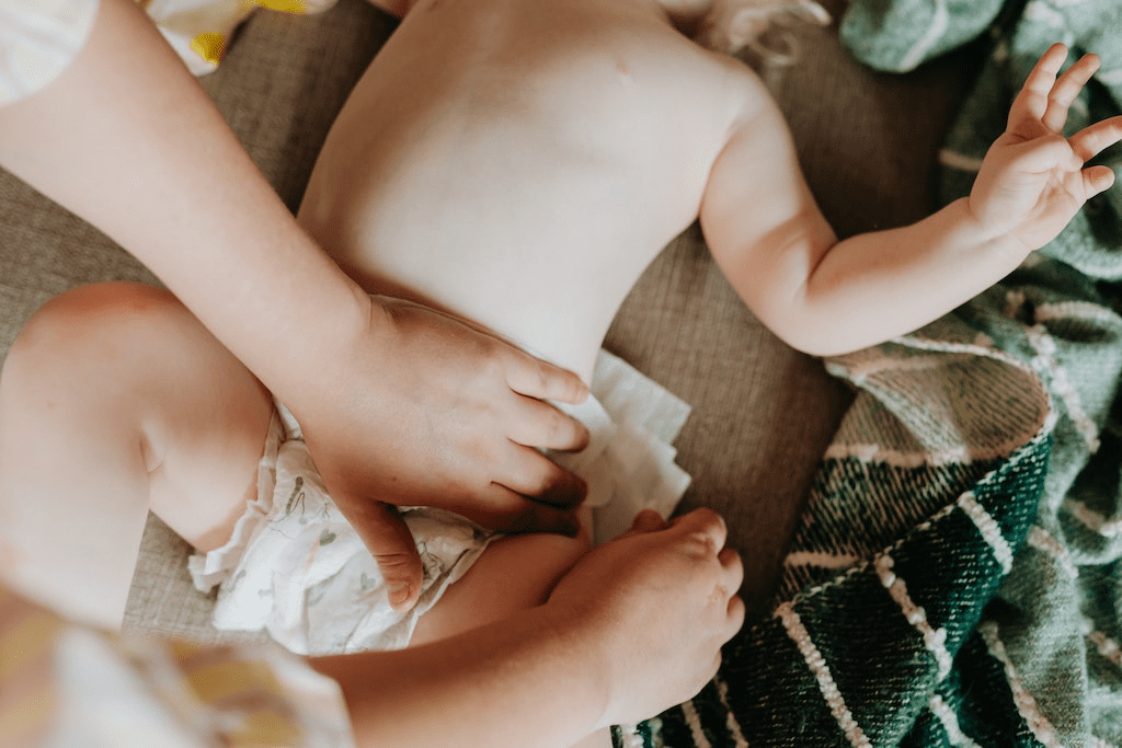 Mãos colocando fralda em um bebê.