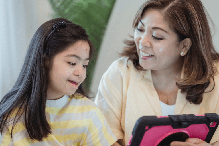 Mãe mostrando algo para a filha em um tablet infantil rosa.