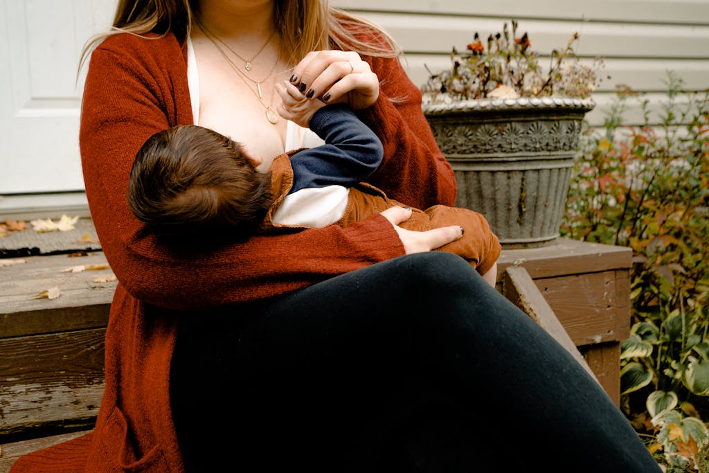 Mãe alimentando seu filho com leite materno enquanto se senta em degraus ao ar livre.