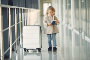 Menina feliz com mala e passaporte em um corredor do aeroporto.